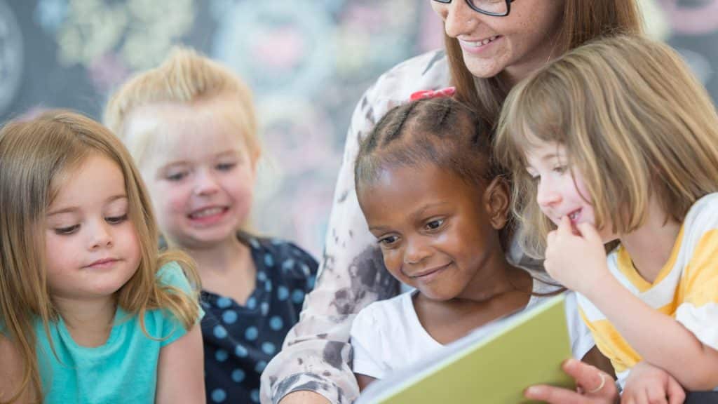 A group of children reading a book with an educator